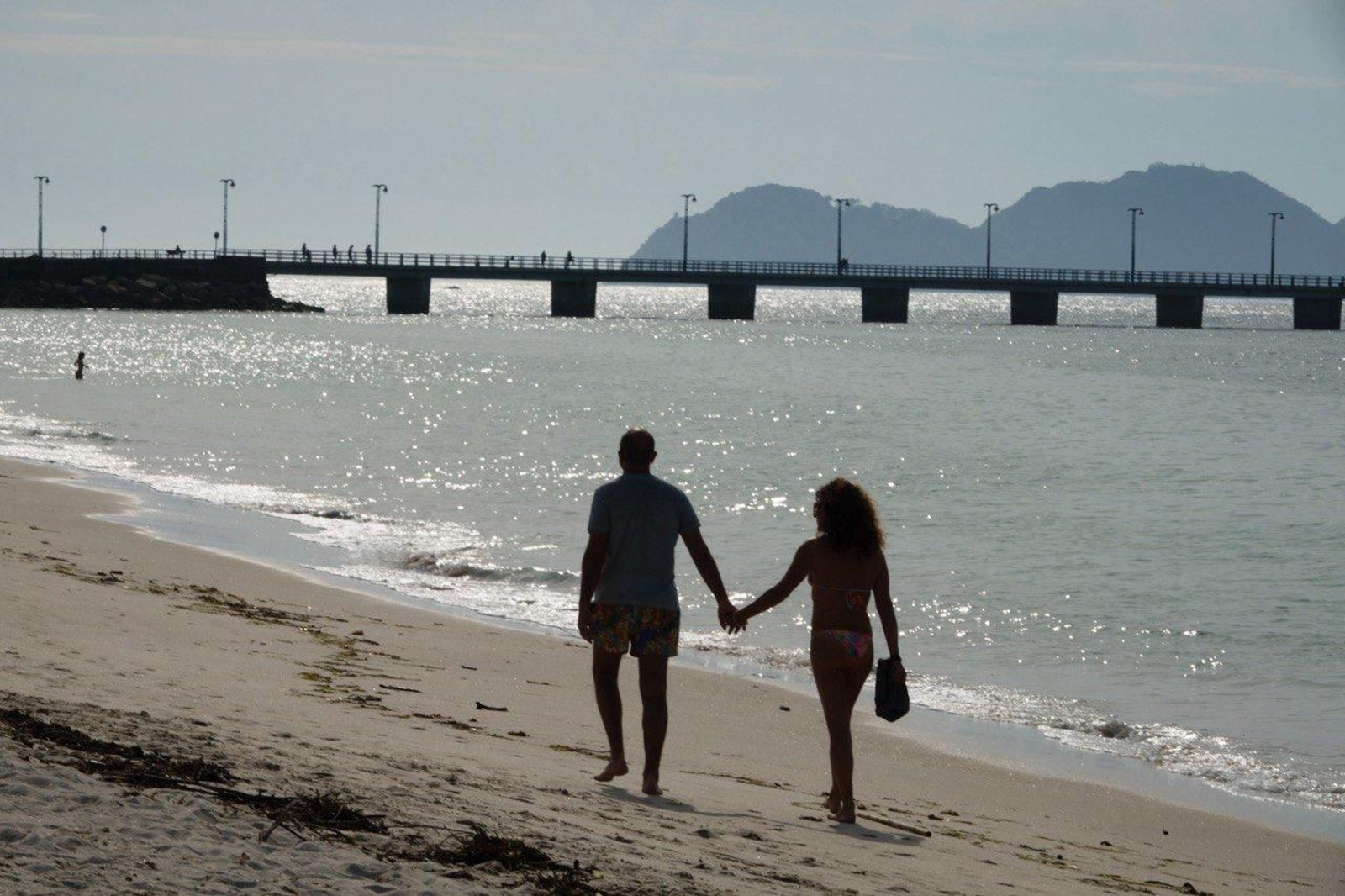 Una pareja pasea por la playa de O Vao.